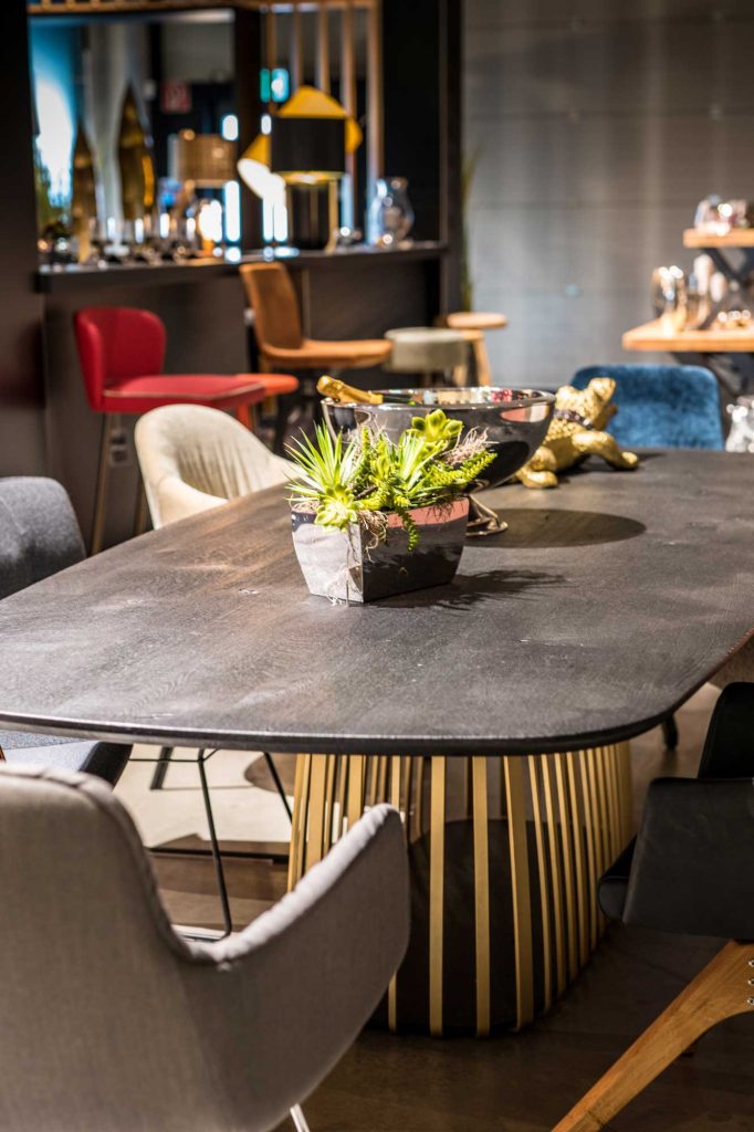 Bild aus dem Edelmeyer Showroom, Tisch mit schwarzer Platte und verschiedenen Esszimmerstühlen.